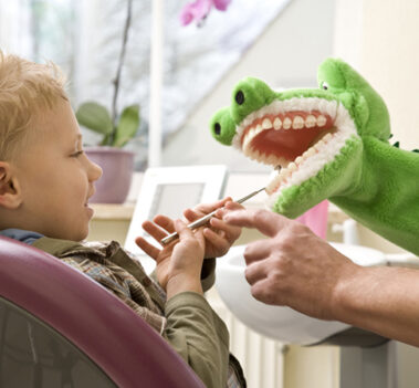 Kind während spielerischer zahnärztlicher Behandlung