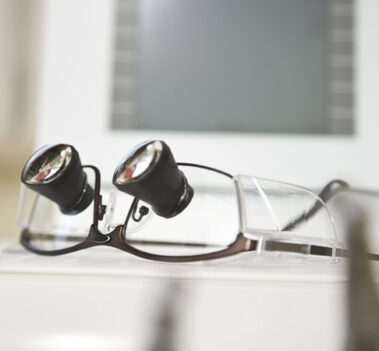 Lupenbrille mit Behandlereinheit im Hintergrund