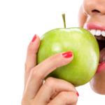 junge Frau beißt in grünen Apfel gesunde Zähne mit Prophylaxe